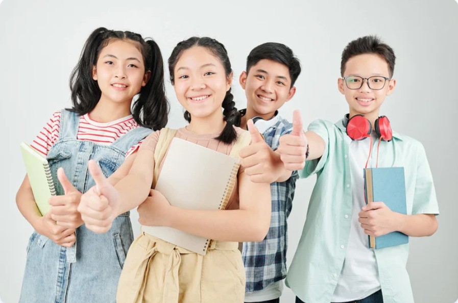Asian students with books giving thumbs up