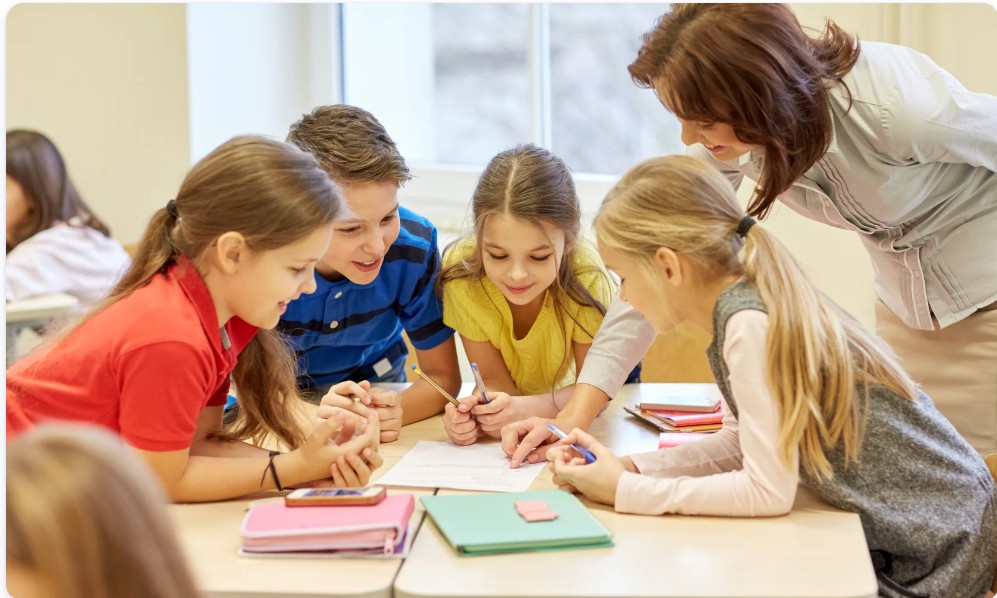 Primary school children collaborating with teacher in classroom