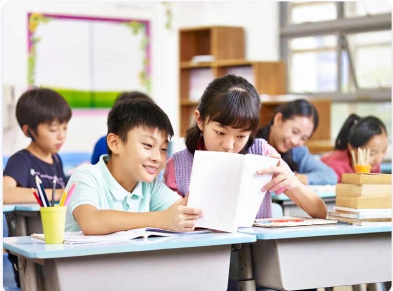 Asian children reading together in classroom